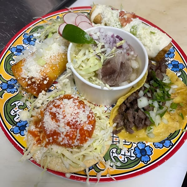 A colorful plate of Nuestro Sabor Mexican food, including tacos, enchiladas, and a soup.